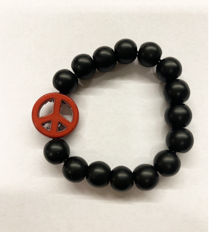 a bracelet made with black onyx beads with one red bead in the shape of a peace sign