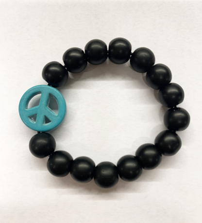 a bracelet made with black onyx beads with one turquoise bead in the shape of a peace sign