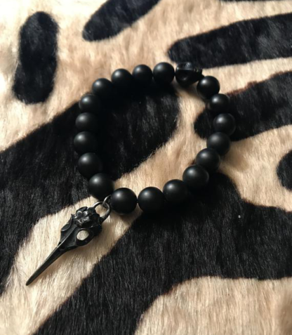 a bracelet made with black onyx beads with a oxidized hummingbird skull charm