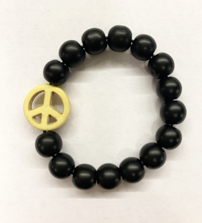 a bracelet made with black onyx beads with one yellow bead in the shape of a peace sign